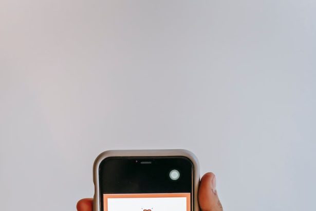 Crop anonymous person holding smartphone in hand and demonstrating screen with app with invitation to be volunteer on gray background